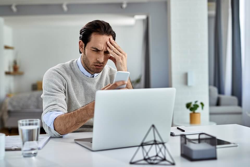Distraught guy working home holding his head pain while facing error